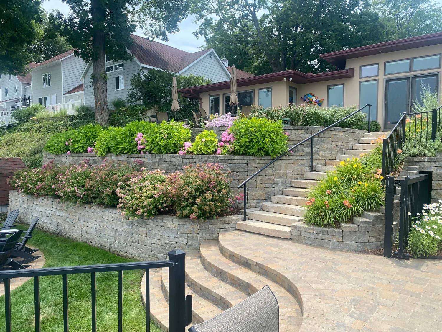 Tiered stone retaining wall with curved steps and blooming pink hydrangeas