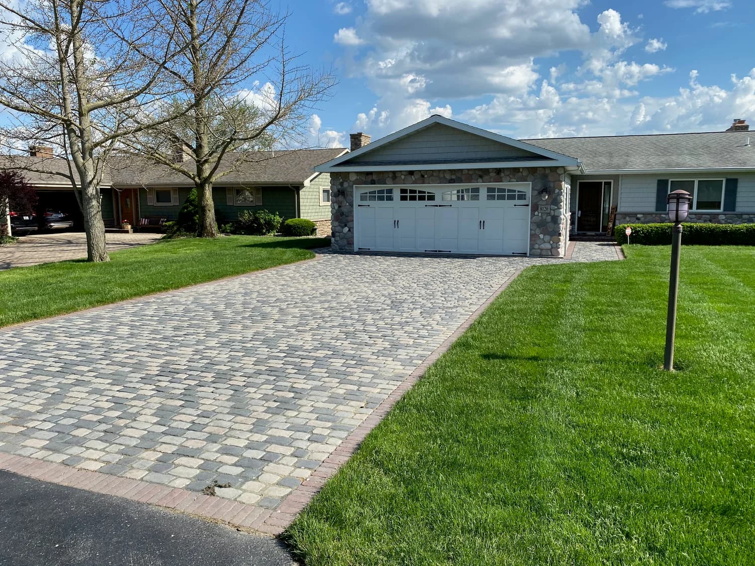 Paver driveway with lush green lawn under blue sky, Southwest Michigan