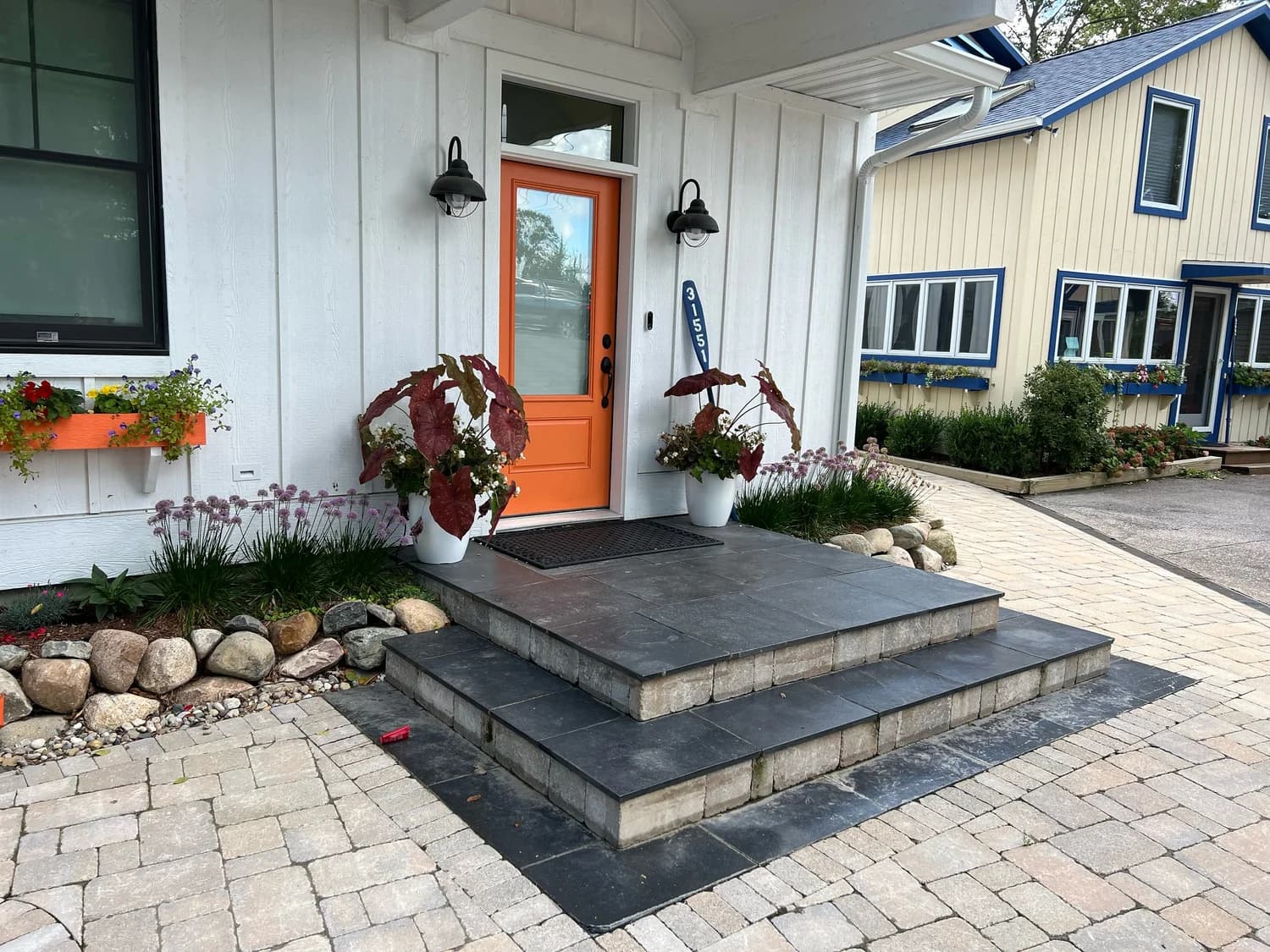 Entry steps with river rock border and paver driveway at a Southwest Michigan home